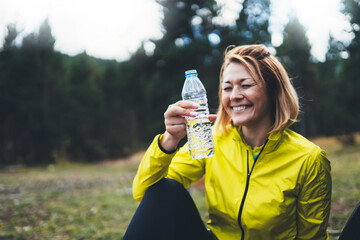 Fun girl quenches thirst after fitness. Smile person laughing drinking water bottles relax after...
