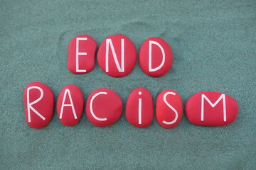 End Racism, social issue text composed with red colored stone letters over green sand