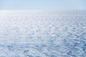 Seascape background of clear sky and vivid blue sea with sunlight reflection on surface