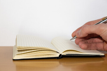 Open notebook and hand on a wooden table