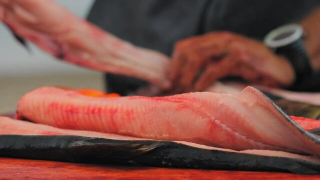 Yukon Territories, Alaska.Opened king salmon with fisherman separating the fish bones from the meat in the background.