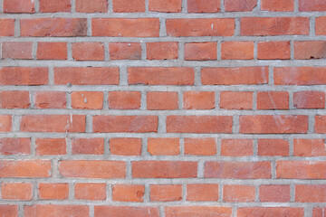 Fototapeta premium Old red brick wall. Bricks with individual texture with concrete layering .
