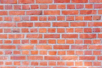 Old red brick wall. Bricks with individual texture with concrete layering .