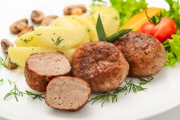 Homemade cutlets with potatoes and vegetables on a white background.