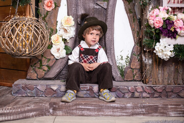happy little boy wearing retro costume on the doorstep of a toy house