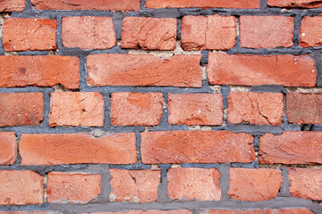 Old red brick wall. Bricks with individual texture with concrete layering .