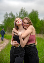 Two teenage girls with long hair on a walk hug each other. The concept of friendship, same-sex relationships. 