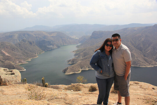 pareja en acantilado con hermoso paisaje monta&ntilde;oso y oceano de fondo 