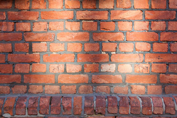 Old red brick wall. Bricks with individual texture with concrete layering .