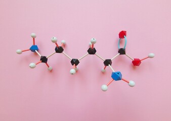 Molecular structure model of essential amino acid L-lysine molecule, required for growth and tissue repair. Lysine (Lys, K) is used in the biosynthesis of proteins. Black=C, red=O, blue=N, white=H.