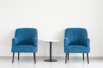 Blue turquoise double armchair with coffee table between armchairs in living room with copy space.