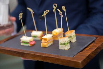 waiter seving canape on slate platter