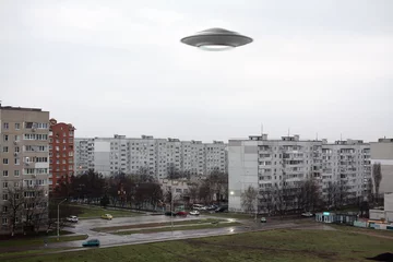 Gordijnen UFO flying in the sky over a city block. Photo with 3d rendering object  © andrey_l