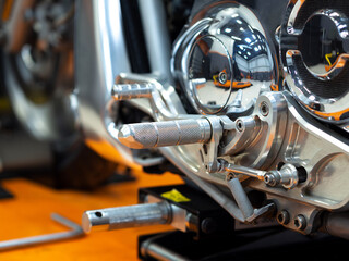 Chrome front footrest of new motorcycle on the floor in salon indoor. Details, close up, selective focus.