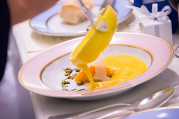 Chef pouring yellow pumpkin sauce in creative food