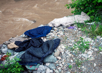 Homeless people dry clothes on rocks near the river.