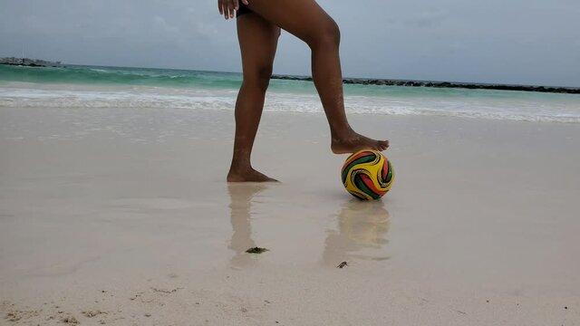 Black African American Latino woman plays beach soccer on white sand 