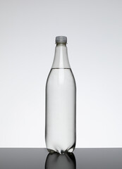 Single 1 litre clear plastic bottle with no label containing a clear liquid against a plain background