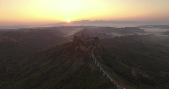 An aerial view shows the road leading up to Civita di Bagnoregio, Italy at sunset.
