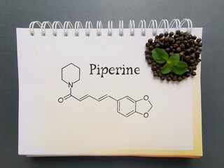 Structural chemical formula of piperine molecule with black pepper grains. Piperine is an amide alkaloid, isolated from Indian medicinal plant Piper nigrum.