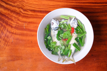 Spicy and sour soup mackerel serve on white bowl set on brown table - homemade food concept.