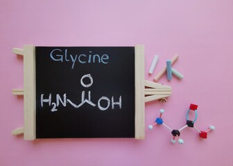 Molecular structure model of glycine molecule with structural chemical formula on a black...