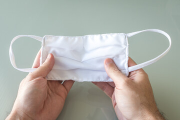 Hands Holding a White Medical Protection Mask