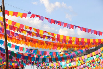 Banderolas coloridas, penduradas contra o céu azul. Enfeites para festa junina. Festa típica...