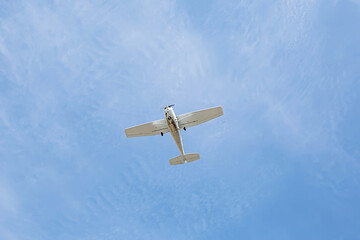 Small single engine vintage airplane in a blue cloudy sky