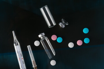against the background of a photograph of a person with suspected coronavirus, a syringe with the drug, multi-colored tablets, broken ampoules and a thermometer