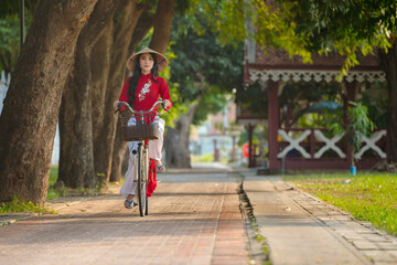 Obraz premium Portrait of Vietnamese girl traditional red dress,Beautiful young asian woman wearing Vietnam with bicycle