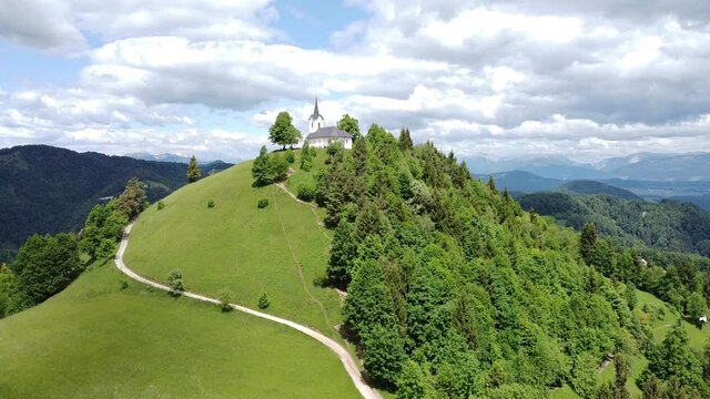 Aerial view of the path leading to the Church of St. James (Sv. Jakob) on the steep hill near Polhov Gradec and Karavanke mountains in the background, Slovenia