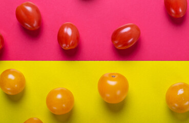 Red and yellow cherry tomatoes on the multicolored geometric background