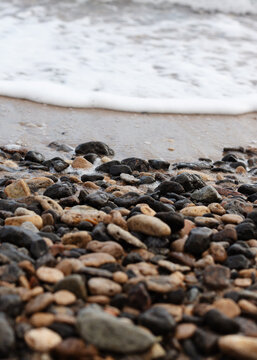 Different texture on the beach - water and sand, stones and pebbles, waves and splashes.