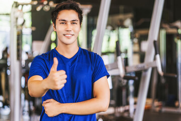 Fototapeta na wymiar Portrait of Young Asian man wearing sportswear and Raising hands like in gym fitness sport complex