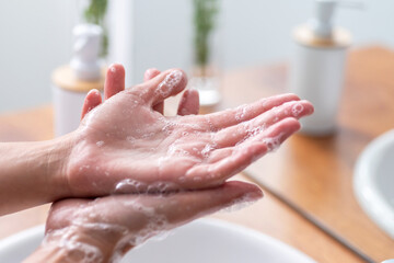 Detail of Woman's hands using soap and washing hands under the water tap
