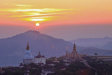 A Buddhist temple on the top of the hill in the morning when the sun is rising against the golden sky.