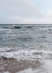 Different texture on the beach - water and sand, stones and pebbles, waves and splashes.