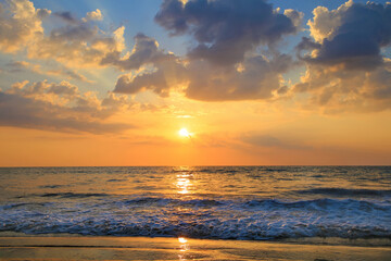 The atmosphere in the evening with the sunset. Shining against the sea surface Saw the waves tapping on the sandy beach