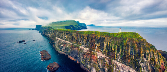 Panoramic view from flying drone of Mykines island with old lighthouse. Gloomy summer scene of Faroe Islands, Denmark, Europe. Stunning seascape of Atlantic ocean. - obrazy, fototapety, plakaty