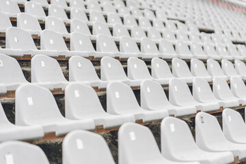 Obraz premium Stadiums amphitheater with many empty white plastic numbered seats for spectators in the stadium for football sport fans. Pattern of plain monochrome sport tribune.