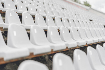 Stadiums amphitheater with many empty white plastic numbered seats for spectators in the stadium for football sport fans. Pattern of plain monochrome sport tribune.