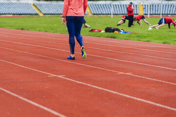 Fototapeta premium Young fitness woman in blue shoes and blue leggings walking on running court or treadmill. Woman wear sport shoe on to run in running court background. Health exercise life style