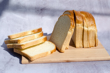 Side view of slicing fresh bread on a wooden board.