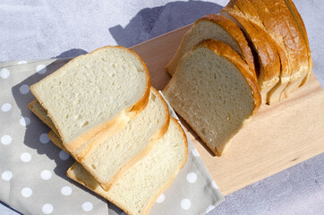 Slicing fresh bread on a wooden board top view. Slicing white bread.