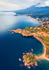 View from flying drone. Amazing morning view of Bella island and Etna volcano on background. Calm summser seascape of Mediterranean sea. Aerial view of Taormina town, Sicily, Itale, Europe.