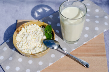 A glass of milk, a plate of cottage cheese and a spoon on a wooden shelf. Healthy eating concept. Breakfast in the village.