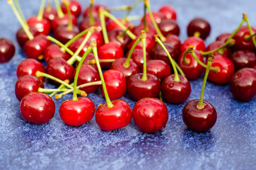 A lot of cherries close-up on a blue background. Fresh fruit.