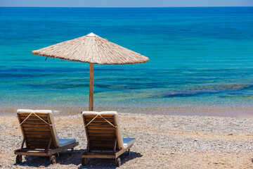 Two lounge chairs with sun umbrella on a beach