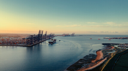 Sunrise over Felixstowe Container Port as two tugs help a container ship to cast off from the...